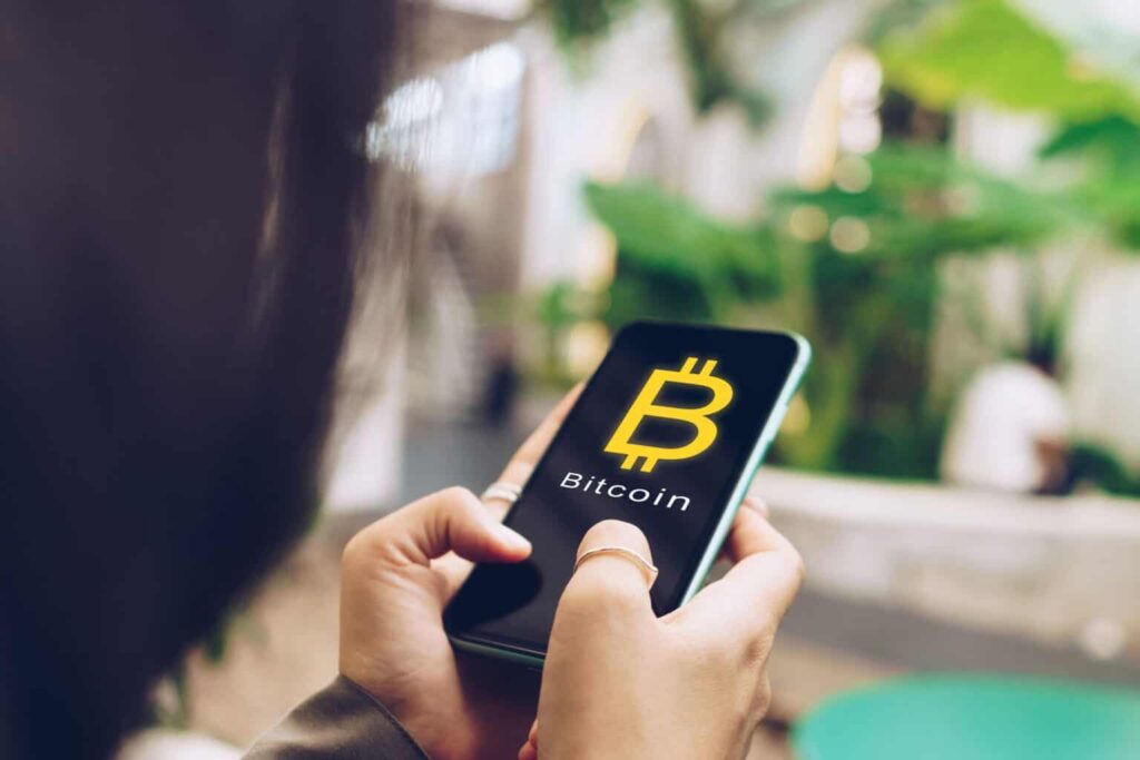Woman using smartphone with Bitcoin Logo on Screen
